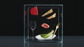 Et utvalg av bestikk, tallerkener og matprodukter i en glassboks for å representere EXPERIENCE-pillaren av 'Taking Taste Further'.
